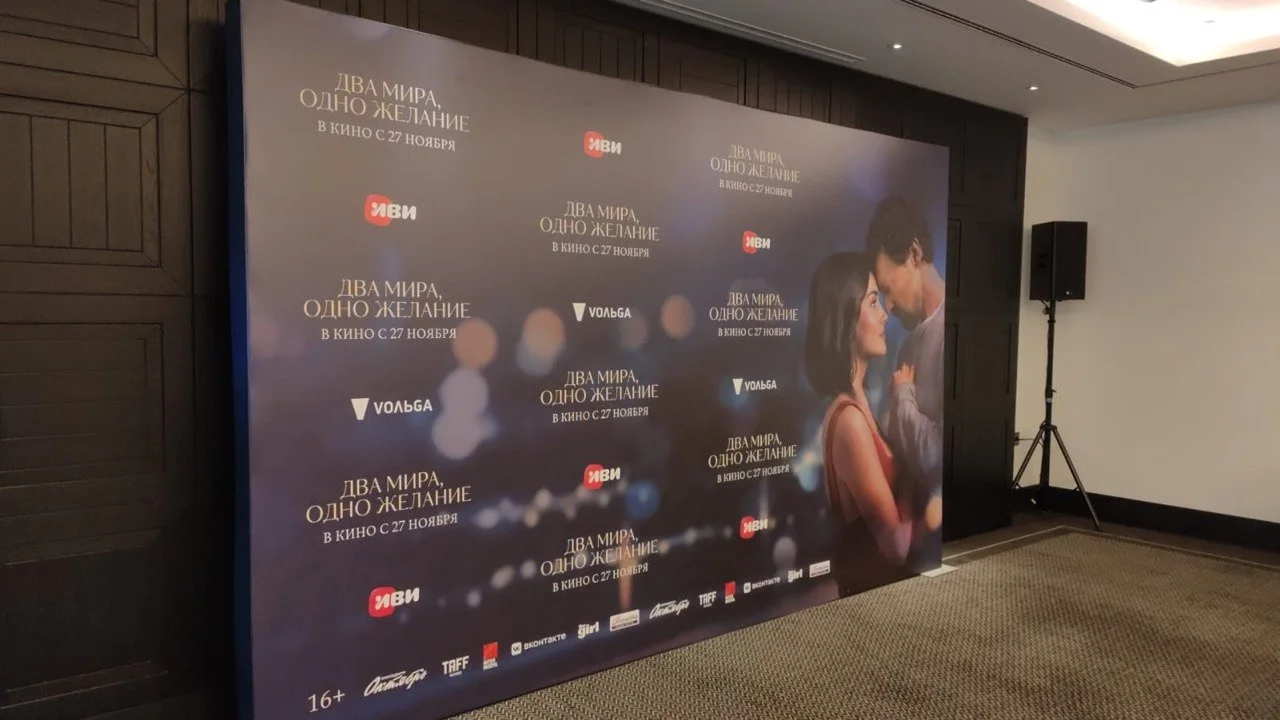 Пресс-волл с логотипами и афишей кинопремьеры «Два мира, одно желание»